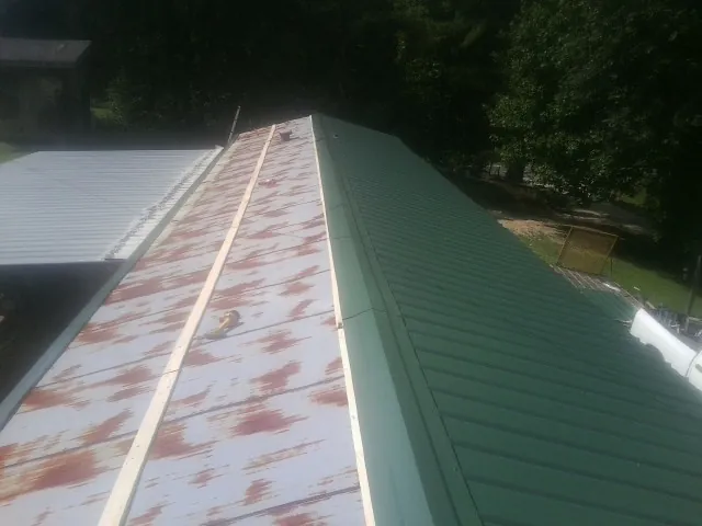 Old rusted panels beside newly installed green metal roofing — Wind Damage Roof Repair by Roofing Brothers in Beaver Dams