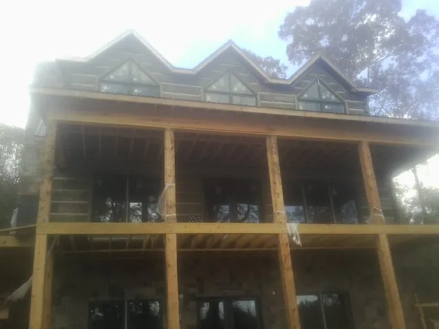 Dormers and porch framing on a large log home under construction — Roof Coating work by our crew in Beaver Dams