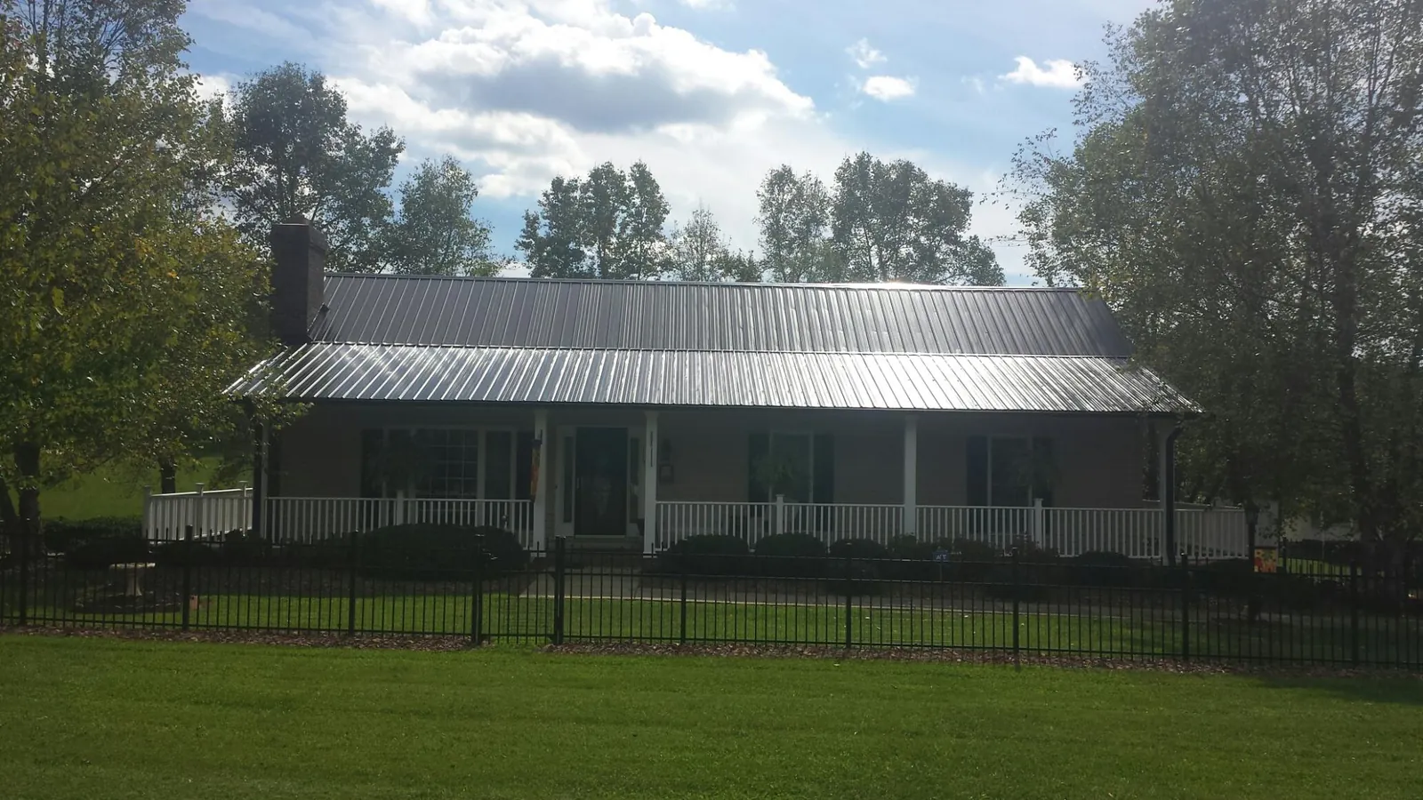 Gray metal roof on a brick ranch with a full width front porch — Gutter Guard Installation work by our crew in Beaver Dams