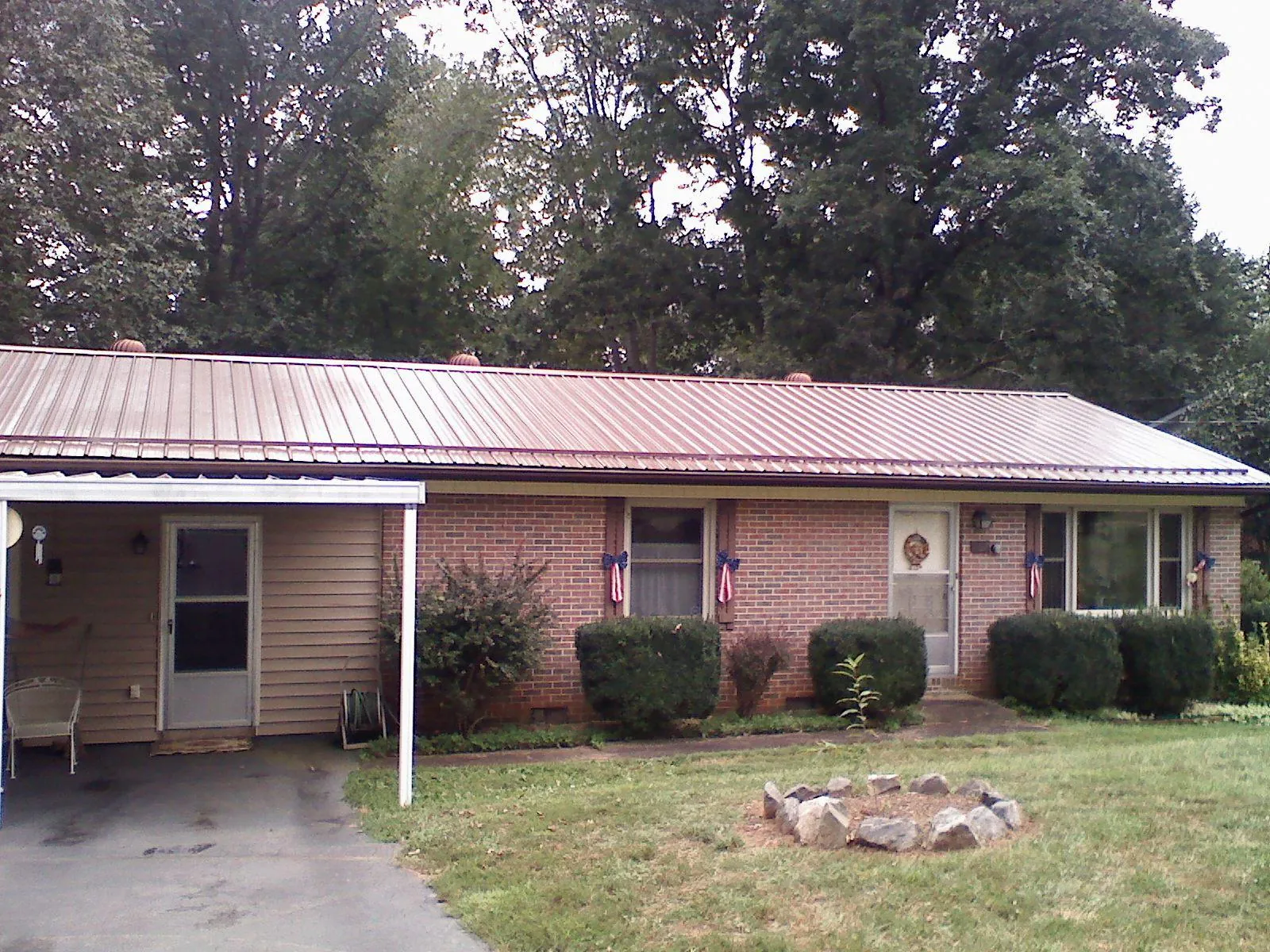 Bronze metal roof and carport on a brick ranch home — Roof Repair work by our crew in Beaver Dams